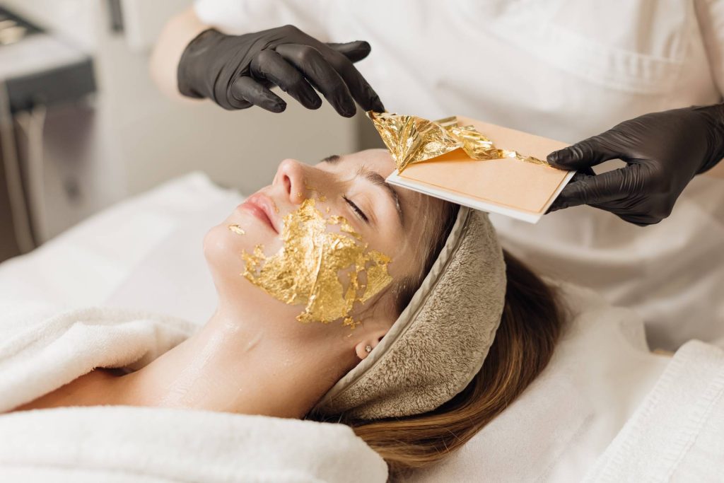 Técnico aplica un tratamiento de láminas de oro en la cara de una mujer